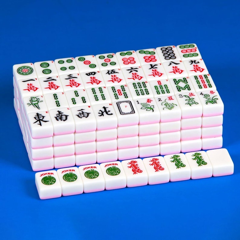 May include: A set of white Mahjong tiles arranged in a rectangular block with a single row of tiles placed in front. Each tile features distinct red, green, and black engraved symbols, including Chinese characters, floral designs, and Joker labels.