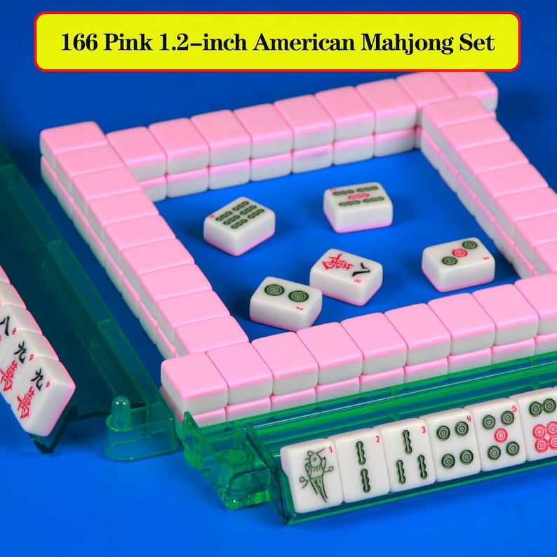 May include: A 166-piece American Mahjong set with pink and white tiles measuring 1.2 inches. The set includes green translucent racks and tiles featuring various engraved symbols, numbers, and characters, arranged in a square formation.