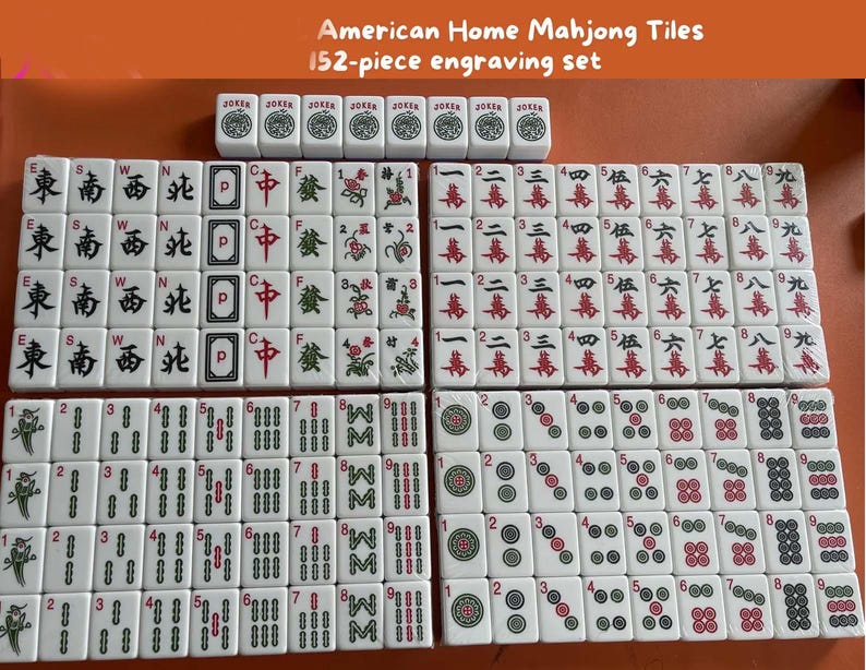 Op de afbeelding: Een 152-delige Mahjong-tegelset met gegraveerde karakters en symbolen. De tegels zijn wit met zwarte, rode en groene markeringen. De set bevat Jokers en diverse symbolen en cijfers.