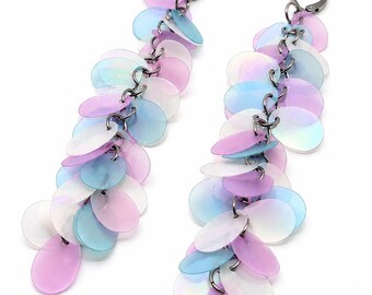 May include: A pair of long dangle earrings featuring multiple translucent, iridescent circular discs in shades of pastel pink, light blue, and white. The discs are linked together in a cascading chain design and attached to dark metal lever-back closures.