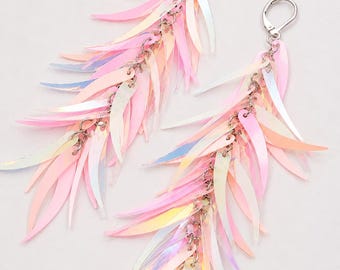 May include: A pair of long dangle earrings featuring multiple layers of pale pink, iridescent, leaf-shaped sequins attached to silver-toned metal jump rings. Each earring is finished with a silver-toned lever-back closure for secure attachment.