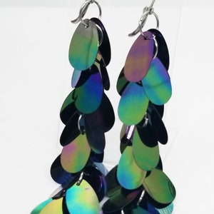 May include: A pair of long, iridescent dangle earrings with multiple layers of oval-shaped sequins. The sequins are a mix of green, blue, and purple.