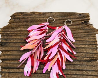 May include: A pair of dangle earrings featuring layered, leaf-shaped sequins in shades of bright pink, soft pink, and deep red. The sequins are attached to silver-toned lever-back closures, creating a cascading, fringe-like effect with a glossy finish.