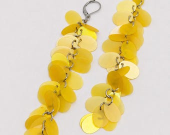 May include: A pair of long dangle earrings featuring multiple translucent yellow circular discs attached to silver-toned metal jump rings. The earrings have silver-toned lever-back closures at the top, with the yellow discs cascading downward.