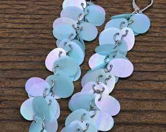 May include: A pair of long dangle earrings featuring multiple iridescent light blue circular sequins linked together with silver-toned metal rings. Each earring is finished with a silver-toned leverback closure, creating a cascading effect.