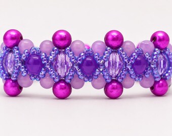 May include: A beaded bracelet featuring a repeating pattern of metallic magenta spheres, light lavender round beads, deep purple circular beads, and translucent faceted oval beads, all interconnected by small, shimmering blue seed beads.