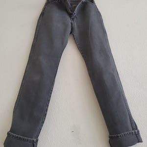 May include: A pair of dark gray denim jeans with a cuffed hem.