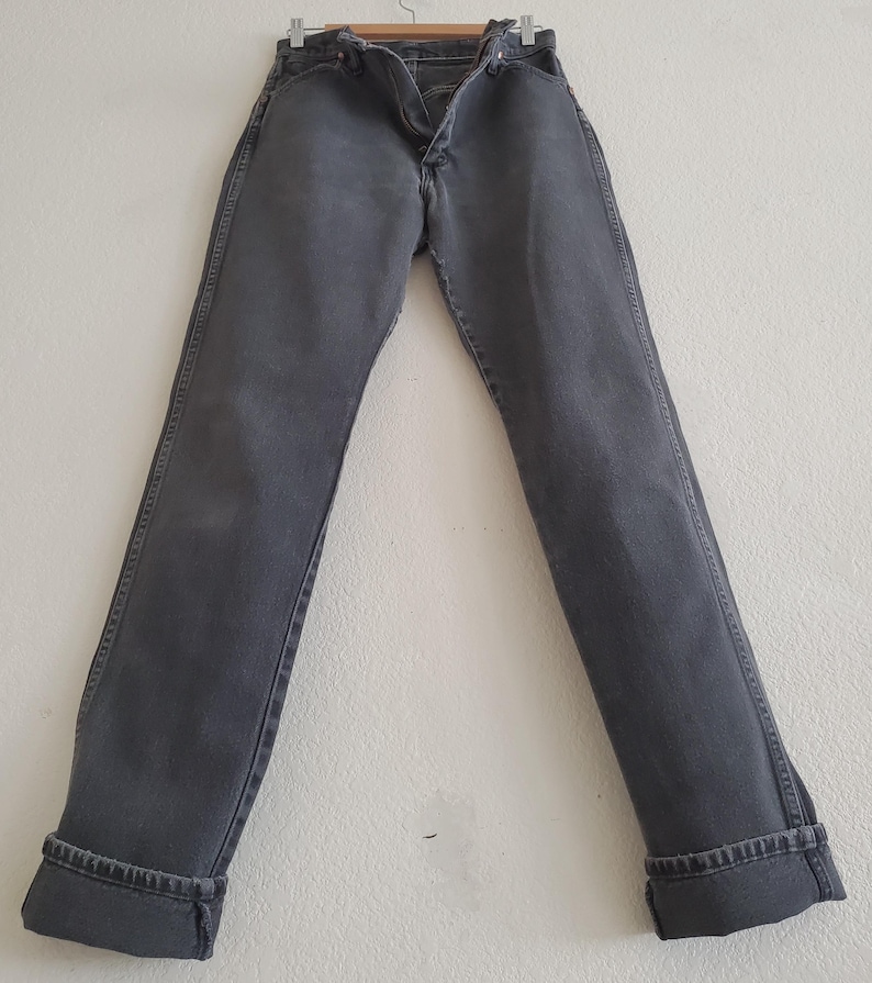 May include: A pair of dark gray denim jeans with a cuffed hem.