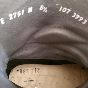 May include: Close-up of the inside of a black leather boot with white text that reads "E 2751 N 8 1/2 107 3993" and "21 287" on the insole. The boot is labeled "Made in Japan."
