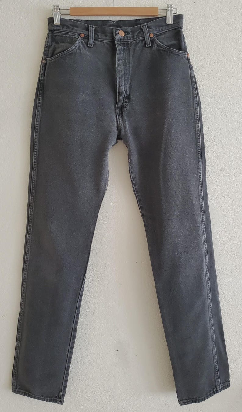 May include: A pair of dark gray denim jeans with a straight leg fit. The jeans have a button fly and belt loops.