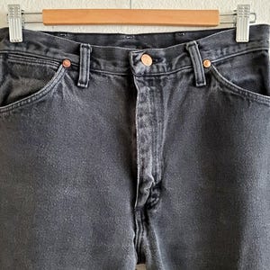May include: A pair of black denim jeans with a classic five-pocket design. The jeans have a straight leg and a relaxed fit.