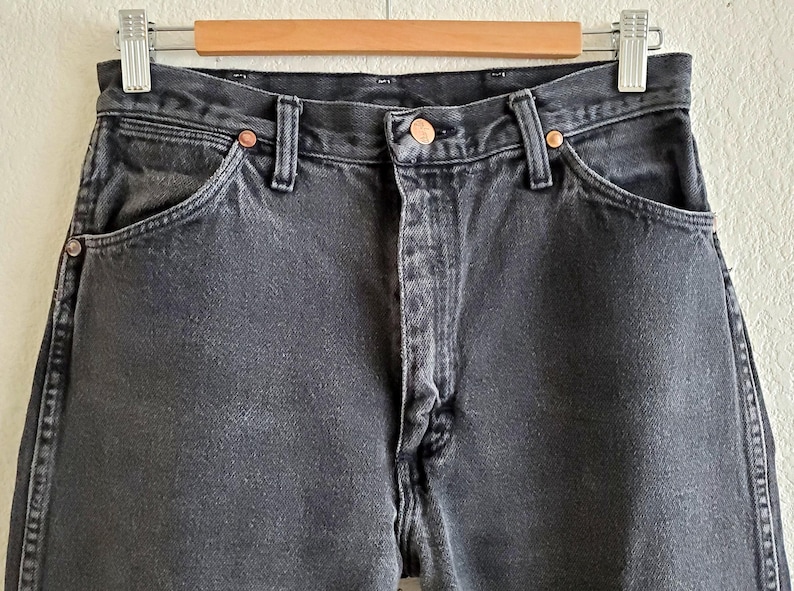 May include: A pair of black denim jeans with a classic five-pocket design. The jeans have a straight leg and a relaxed fit.