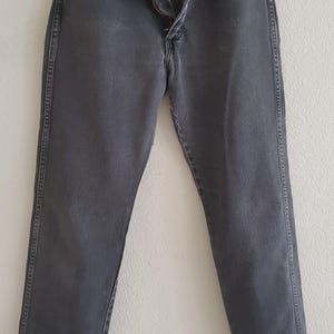 May include: A pair of dark gray denim jeans with a button fly and a straight leg.
