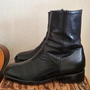 May include: A pair of black leather boots with a pointed toe and a zipper on the side. The boots have a slight heel and a textured leather upper.
