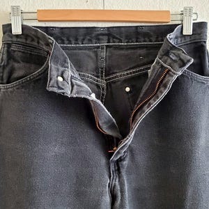 May include: A pair of black denim jeans with a zipper fly and button closure. The jeans have a classic five-pocket style and are made of a soft, comfortable fabric.