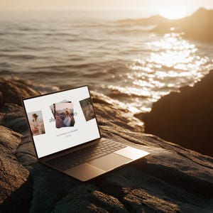 May include: A laptop computer with a black keyboard and a silver-colored frame is open on a rocky surface near the ocean. The screen displays three images and the text "the portfolio" with additional text below. The background features the ocean and a sunset.