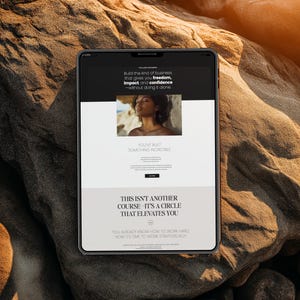 May include: A tablet displaying a website with text that reads "Build the kind of business that gives you freedom, impact and confidence - without doing it alone." The tablet is on a textured, brown rock surface.