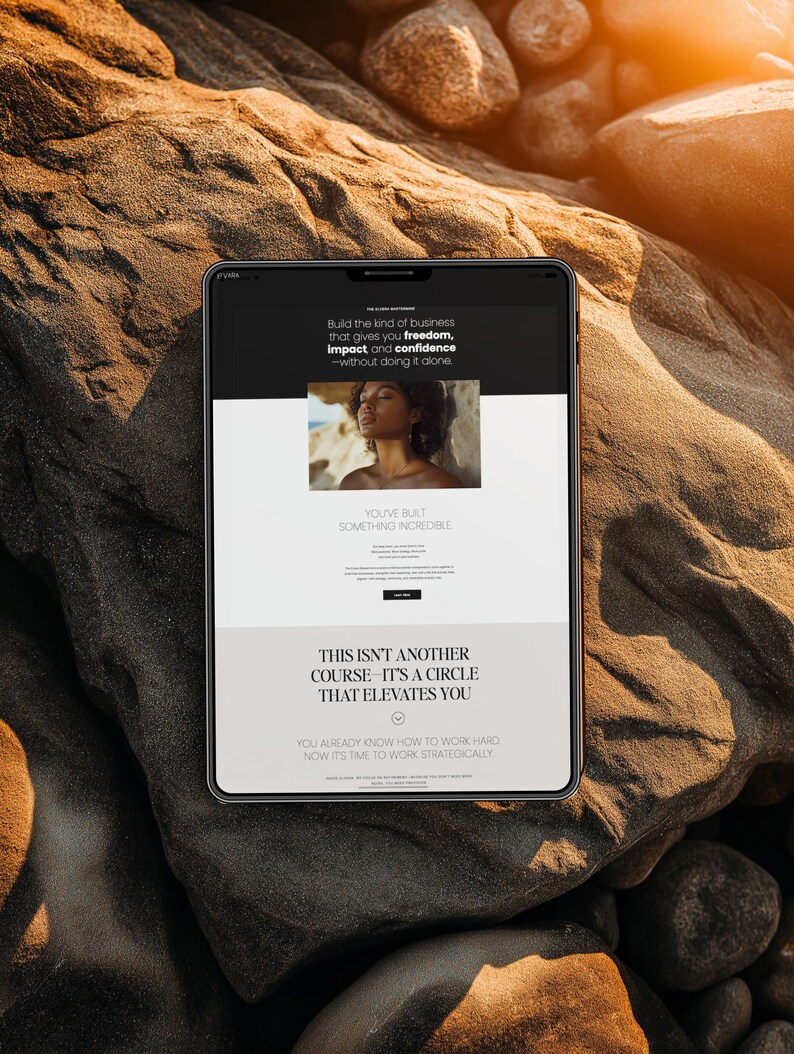 May include: A tablet displaying a website with text that reads "Build the kind of business that gives you freedom, impact and confidence - without doing it alone." The tablet is on a textured, brown rock surface.