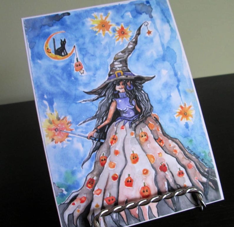 May include: Watercolor painting of a witch with long black hair wearing a pointed hat and a dress with a pumpkin pattern. She is holding a wand with a spark at the end. The background is a blue sky with stars and a crescent moon.