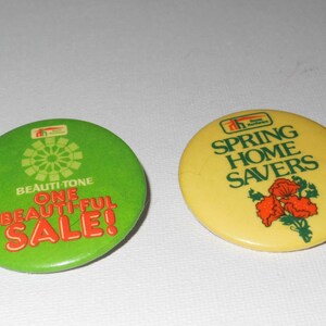May include: Two round, green and yellow buttons with white text and graphics. The green button says "Beauti-Tone One Beautiful Sale!" and has a stylised flower design. The yellow button says "Spring Home Savers" and has a red flower design.
