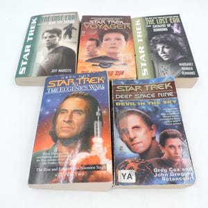May include: Five Star Trek novels are displayed. The book covers feature character images and titles such as "The Lost Era," "Voyager," and "Deep Space Nine." The books are presented on a white surface.