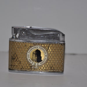 May include: A silver and gold lighter with a diamond pattern. The lighter has a logo for the Sun Life Assurance Company of Canada.