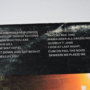 May include: Black vinyl record with white text listing song titles: Wild Winds Are Blowing, Shape of Things to Come, Know Who You Are, Pouk Hill, One Way Hotel, Get Down and Get With It, Coz I Luv You, Look Wot You Dun, Take Me Bak'Ome, Mama Weer All Crazee Now, Gudbuy T' Jane, Look At Last Night, Cum On Feel The Noize, Skweeze Me Pleeze Me.