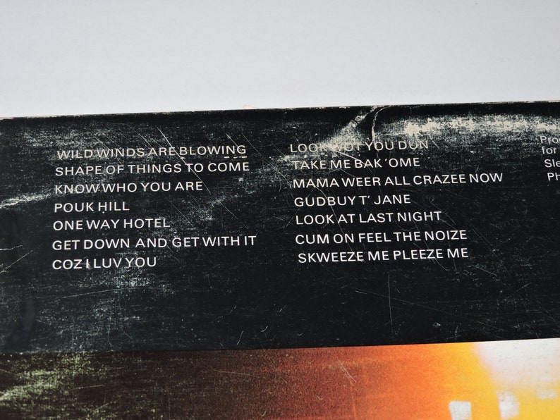 May include: Black vinyl record with white text listing song titles: Wild Winds Are Blowing, Shape of Things to Come, Know Who You Are, Pouk Hill, One Way Hotel, Get Down and Get With It, Coz I Luv You, Look Wot You Dun, Take Me Bak'Ome, Mama Weer All Crazee Now, Gudbuy T' Jane, Look At Last Night, Cum On Feel The Noize, Skweeze Me Pleeze Me.