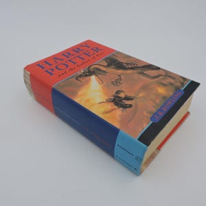 May include: A red, blue, and yellow hardcover book titled "Harry Potter and the Goblet of Fire" by J.K. Rowling. The cover features an illustration of a dragon breathing fire.