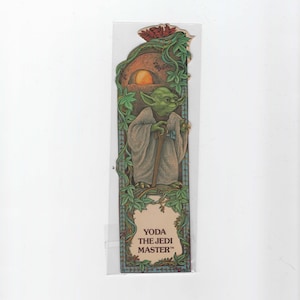 May include: A green Yoda bookmark with a brown background and green vines. The text "YODA THE JEDI MASTER" is printed on the bookmark.