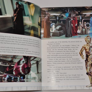 May include: A close-up image of a book open to a page with text and images from the Star Wars movie. The text describes a scene from the movie where Jedi Knights are negotiating with the Trade Federation. The image shows a scene from the movie with a Jedi Knight and a Trade Federation leader. The image also shows a close-up of C-3PO, a golden protocol droid.