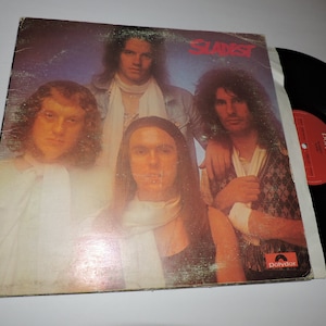 May include: A vintage vinyl record album cover featuring a band called "Slade" with four band members. The album cover is a close-up of the band members with a light blue, purple, and white background. The album cover has a red "Polydor" label.