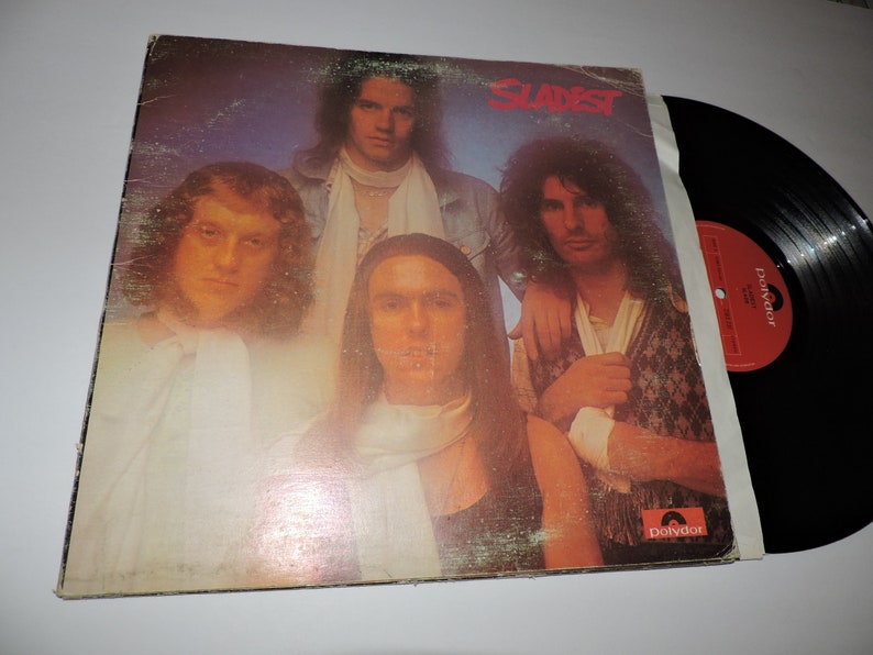 May include: A vintage vinyl record album cover featuring a band called "Slade" with four band members. The album cover is a close-up of the band members with a light blue, purple, and white background. The album cover has a red "Polydor" label.