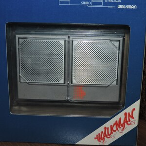 May include: A silver and black cassette player with a Walkman logo on the front. The player is in a blue and white box with the word "Walkman" printed on the side.