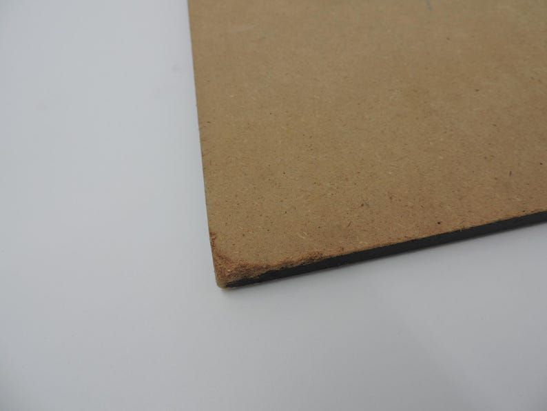 Op de afbeelding: Een hoekweergave van een rechthoekig, bruin, onafgewerkt houten bord. Het bord heeft een donkere rand en een ruw, getextureerd oppervlak. De hoek toont een licht beschadigde rand.