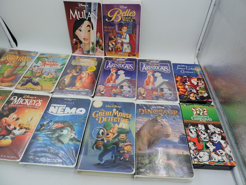 Pu&ograve; includere: Una collezione di VHS Disney con film d'animazione come "Mulan", "Alla ricerca di Nemo", "Gli Aristogatti" e "La carica dei 101 - Natale". Le cassette hanno copertine colorate con illustrazioni dei personaggi.