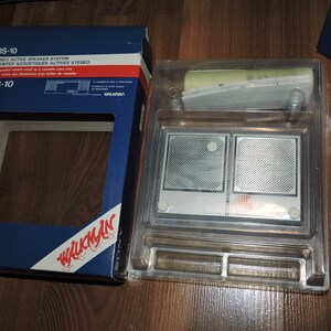 May include: A blue box with the text "SRS-10 STEREO ACTIVE SPEAKER SYSTEM ENCEINTES ACOUSTIQUES ACTIVES STEREO" and "SRS-10 WALKMAN" on it. The box is open and shows a clear plastic case with two silver speakers inside.
