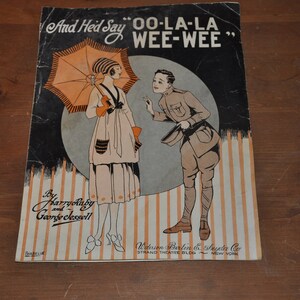 May include: A vintage sheet music cover featuring a woman in a white dress holding an orange umbrella and a man in a military uniform. The title of the song is "OO-LA-LA WEE-WEE" and the songwriters are Harry Ruby and George Jessell.
