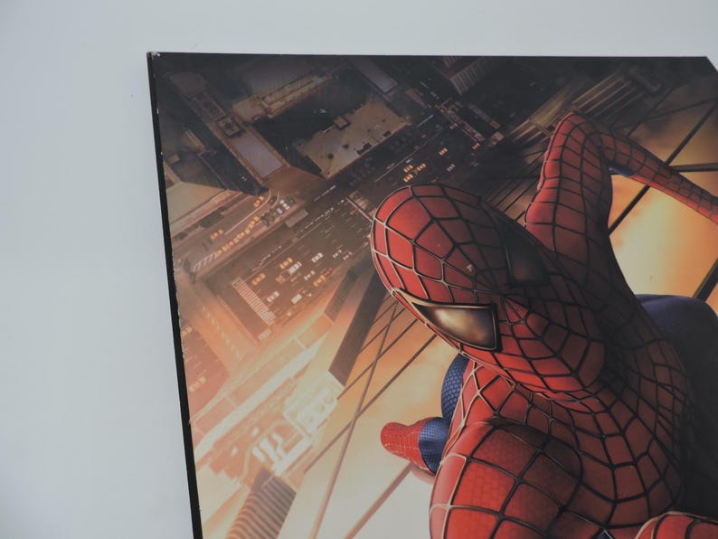 Op de afbeelding: Een ingelijste print met Spider-Man in zijn iconische rood-blauwe pak, tegen een achtergrond van een stadsgezicht. De afbeelding toont de superheld in actie, met de nadruk op zijn gedetailleerde kostuum en de stedelijke omgeving.