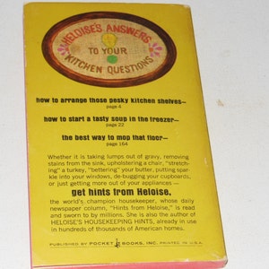 May include: A yellow book cover with the title "Heloise's Answers to Your Kitchen Questions". The cover features a red, white, and blue embroidered design. The book includes tips on how to arrange kitchen shelves, start soup in the freezer, and mop the floor. It also features a quote about Heloise, the world's champion housekeeper.