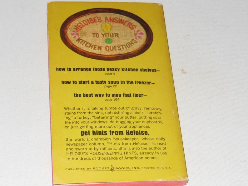 May include: A yellow book cover with the title "Heloise's Answers to Your Kitchen Questions". The cover features a red, white, and blue embroidered design. The book includes tips on how to arrange kitchen shelves, start soup in the freezer, and mop the floor. It also features a quote about Heloise, the world's champion housekeeper.