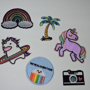 May include: Six colourful iron-on patches featuring a rainbow, a palm tree, a unicorn, a unicorn with a rainbow ring, a rainbow with a cloud and the text "We're all going to die", and a camera with a heart.