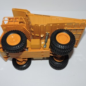 May include: A yellow toy dump truck with black tires and the text "KOMATSU HD402" on the side.