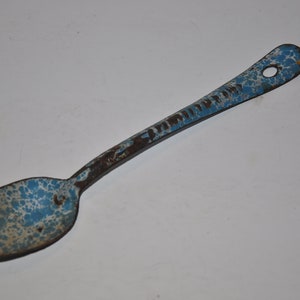May include: A blue and white speckled enamel spoon with a long handle. The handle is chipped and shows signs of rust.