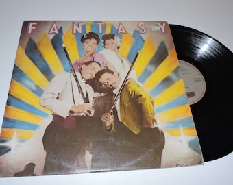 May include: A vintage vinyl record album cover featuring a group of four people dressed in formal attire. The album cover is yellow, blue, and white with the word "FANTASY" in large, bold letters at the top. The people are holding pool cues and are smiling.
