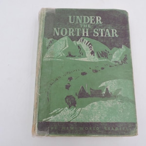 May include: A hardback book titled Under the North Star from The New World Readers series. The cover is dark green with a lighter green illustration of mountains, a winding path, and small buildings. The text is printed in a light green font.