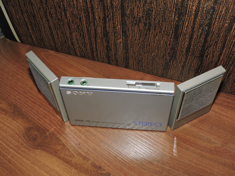 May include: A silver Sony SRS-10 stereo radio with two speakers that fold out. The radio has a volume knob and a headphone jack.