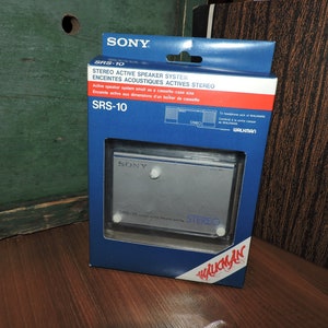 May include: A blue and white box for a Sony SRS-10 stereo active speaker system. The box features the text "SRS-10" and "STEREO ACTIVE SPEAKER SYSTEM" in white lettering. The box also includes a picture of the speaker system, which is silver and has the text "SONY" and "STEREO" on it.
