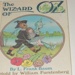 May include: Vintage hardcover book titled "The Wizard of Oz" with a colourful illustration on the cover. The illustration features the Scarecrow, Dorothy, the Tin Man, and a dog. The book cover has the text "By L. Frank Baum" and "Retold by William Furstenberg".