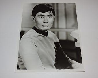Puede incluir: Foto en blanco y negro de un hombre con una camisa de color gris claro con cuello. Está mirando directamente a la cámara.